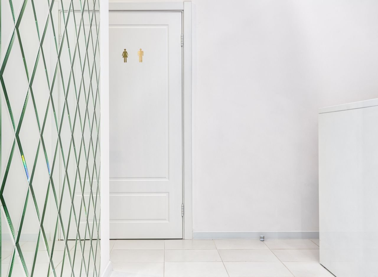 About Interior of empty hallway with tiled floor white door of bathroom and glass wall with geometric elements